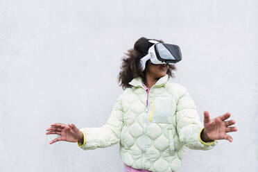 Girl wearing virtual reality headset gesturing in front of white wall - PNAF03805