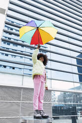 Mädchen mit Regenschirm vor einem modernen Gebäude stehend - PNAF03814