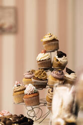 Bunch von sortierten leckeren Cupcakes auf Metallhalter auf dem Tisch in der Bäckerei platziert - ADSF34668