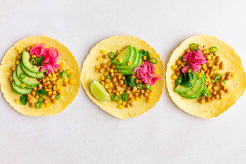 Draufsicht auf Tortillas mit geschnittenen Avocados und Kichererbsen auf weißem Hintergrund in der Küche - ADSF34674