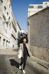 Smiling young woman walking on footpath - DCRF01144