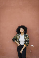 Smiling woman with curly hair standing in front of wall - DCRF01151
