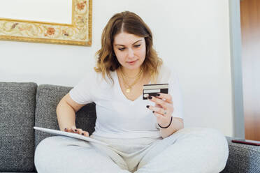 Lächelnde junge Frau beim Bezahlen mit Kreditkarte auf einem Tablet-PC - MEUF05324