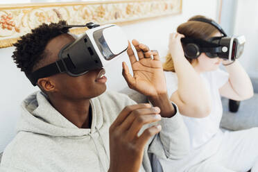 Pärchen mit Virtual-Reality-Simulatoren auf dem Sofa zu Hause - MEUF05330
