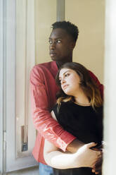 Young couple standing together by window at home - MEUF05347