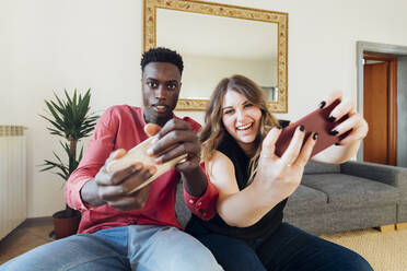 Glückliches Paar spielt Videospiele auf dem Smartphone zu Hause - MEUF05350