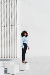 Businesswoman standing on concrete block - MEUF05419