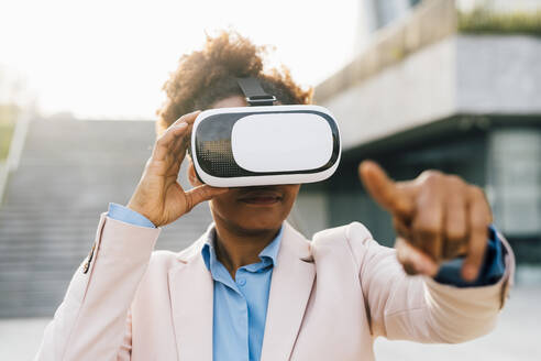 Geschäftsfrau trägt Virtual-Reality-Simulator und gestikuliert - MEUF05457