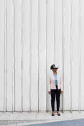 Geschäftsfrau mit Virtual-Reality-Simulator vor einer weißen Wand - MEUF05460