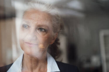 Senior businesswoman with gray hair looking through window - JOSEF08891