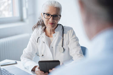 Doctor wearing eyeglasses discussing with patient - JOSEF08911