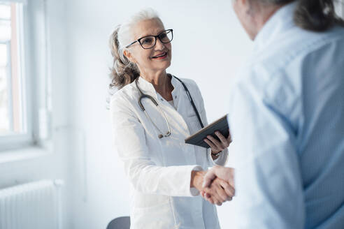 Smiling senior doctor shaking hands with patient - JOSEF08915