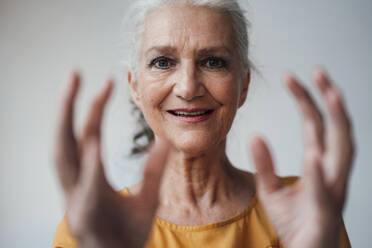 Happy senior woman gesturing against white background - JOSEF08968