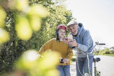 Glücklicher Großvater teilt Handy mit Enkelin an sonnigem Tag - UUF25897