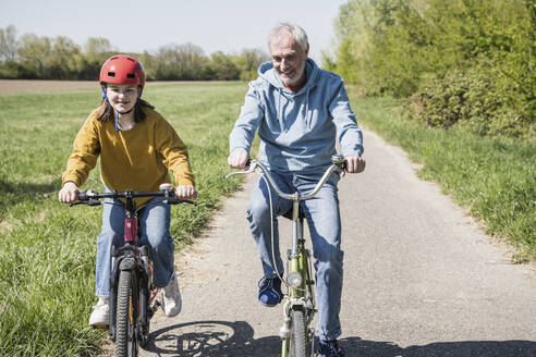 Großvater und Enkelin radeln auf dem Fußweg - UUF25903