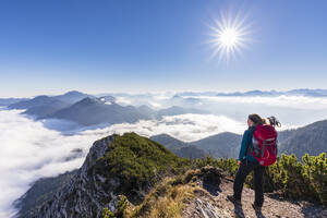 Deutschland, Bayern, Wanderin steht auf einem Berggipfel und bewundert die nebelumhüllten Gipfel der Bayerischen Voralpen - FOF13148