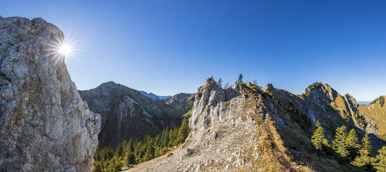 Deutschland, Bayern, Panoramablick auf die Sonne über einem Tal in den Ammergauer Alpen mit einem einsamen Wanderer im Hintergrund - FOF13168