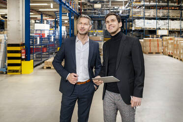 Confident businessman with smiling colleague at factory - PESF03659