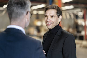 Mature businessman discussing with colleague in warehouse - PESF03669