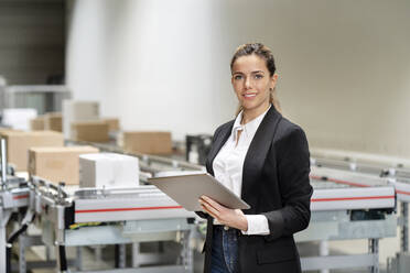 Confident businesswoman with tablet computer at factory - PESF03683