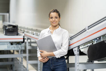 Lächelnde Geschäftsfrau mit Tablet-Computer in einer Fabrik - PESF03695