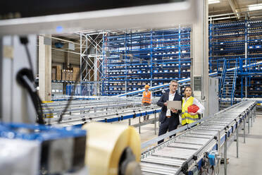 Businessman discussing with colleague in factory - PESF03706