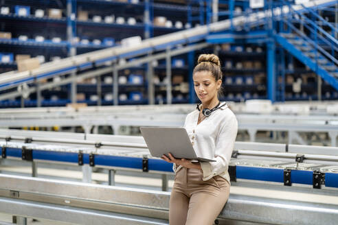 Woman using laptop in warehouse - PESF03748