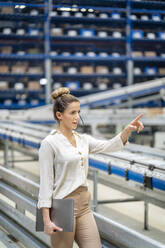 Young businesswoman with laptop pointing at factory - PESF03752