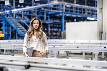 Contemplative businesswoman with laptop in warehouse - PESF03757