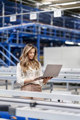 Young businesswoman using laptop working in factory - PESF03758