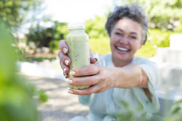 Glückliche reife Frau gibt Flasche mit Smoothie - ESTF00045