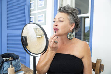 Frau trägt Lippenstift auf, während sie zu Hause vor dem Spiegel sitzt - ESTF00056