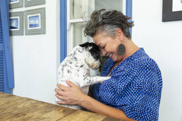 Glückliche Frau umarmt Hund sitzt am Tisch - ESTF00064