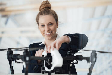 Smiling businesswoman with drone at workshop - JOSEF08982