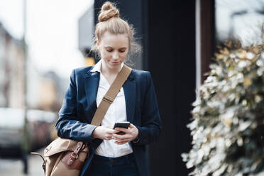 Businesswoman with shoulder bag using smart phone - JOSEF08993