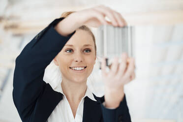 Smiling architect holding building model at office - JOSEF09030