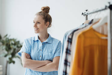 Contemplating fashion designer with arms crossed standing in studio - JOSEF09043