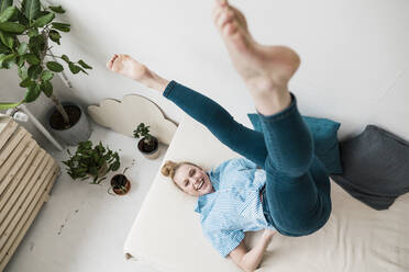 Verspielte Geschäftsfrau übt Yoga auf dem Bett zu Hause - JOSEF09071