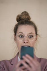 Überraschung: Geschäftsfrau mit Haarknoten schaut auf ihr Smartphone - JOSEF09104