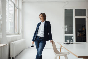 Businesswoman wearing blazer standing by desk in office - JOSEF09167