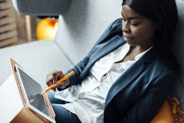 Junge Geschäftsfrau mit Tablet-PC auf dem Sofa im Büro sitzend - JOSEF09201