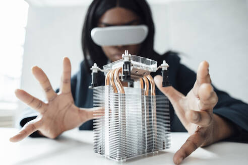 Ingenieur, der einen Virtual-Reality-Simulator trägt, gestikuliert bei einem Halbleiter auf dem Schreibtisch im Büro - JOSEF09239