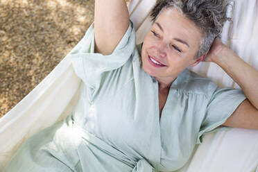 Happy woman with hand behind head lying on hammock - ESTF00089