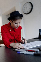 Woman sketching in book sitting at desk - OGF01222