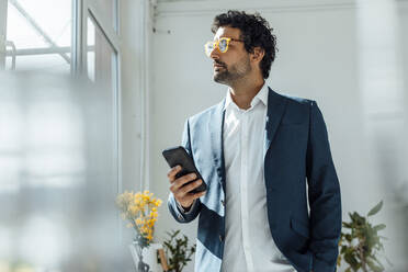 Geschäftsmann mit Brille und Mobiltelefon im Büro - JOSEF09249