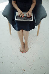 Geschäftsfrau mit Laptop im Sessel sitzend - JOSEF09340