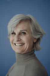 Happy senior woman with gray hair against blue background - JOSEF09354