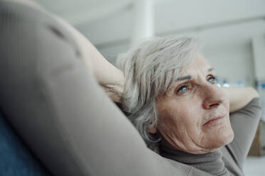 Ältere Frau sitzend mit Händen hinter dem Kopf - JOSEF09364