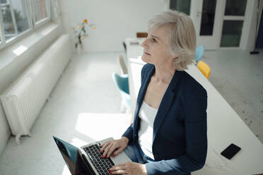Ältere Geschäftsfrau mit Laptop auf dem Schreibtisch im Büro - JOSEF09390