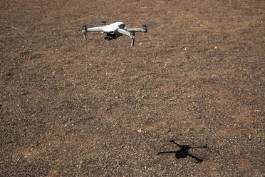 Drohne fliegt über braunes Terrain voller Kieselsteine - JMF00616